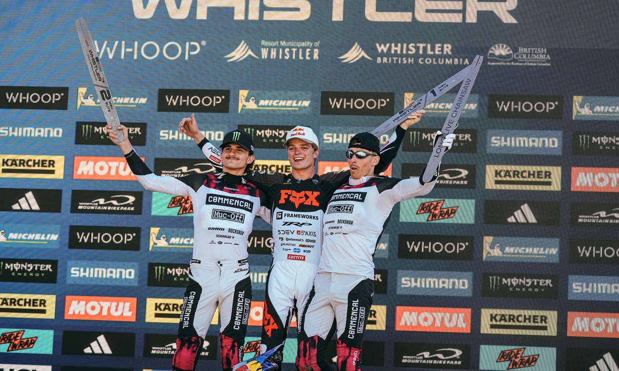 3 young men pictured on a winners podium with trophies